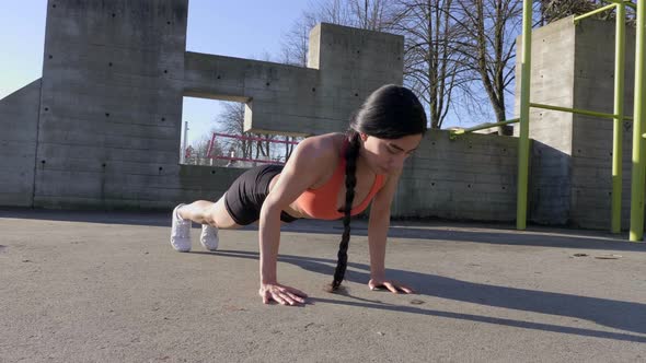Young lean woman doing pushups outdoors Slider shot track left