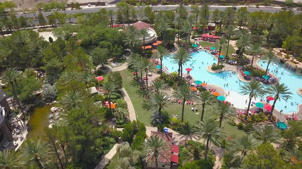 Sideways drone footage of people enjoying a resort pool. 4K