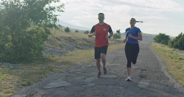 Tracking Slow Motion Shot of Sportive Couple Jogging Outdoors in the Morning Trail Running