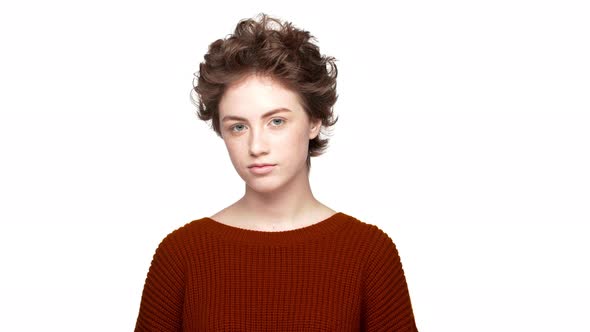 Indoor Portrait of Confident Lady with Brown Curly Hair Looking on Camera with Meaningful Gaze and