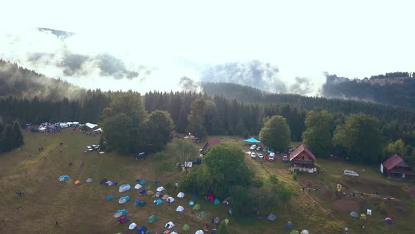 Tilting Aerial Drone Shot Revealing a Romanian Festival Campground with a Gorgeous Mountain Range as