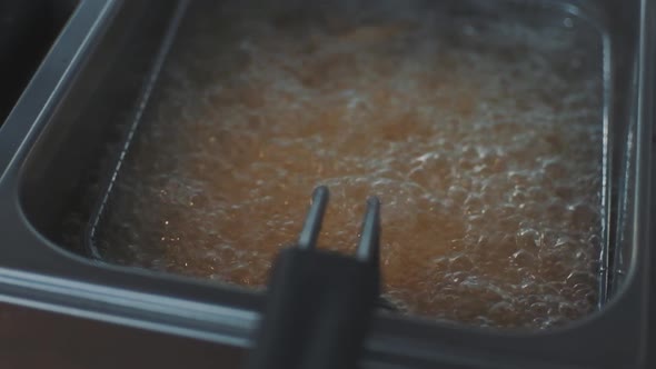 French Fries Fried in a Wire Basket in Hot Oil