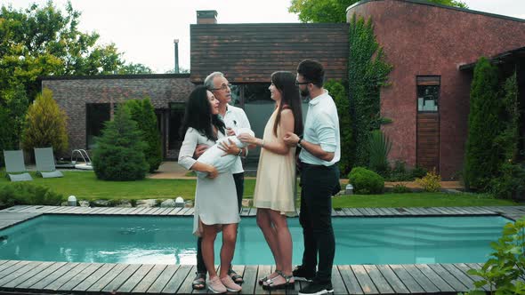 A meeting of a large family outside the city on the background of a modern house with a pool