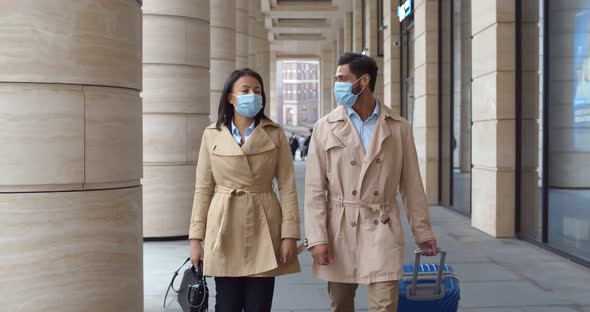 Slider Shot of Business Colleagues in Safety Mask Walk Outdoors with Luggage