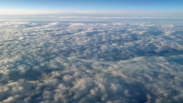 Incredible view from the cockpit of an airplane flying high above the clouds leaving a long white co