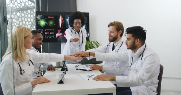 Diverse Team of Doctors which Stacking Hands Together Before Starting the meeting