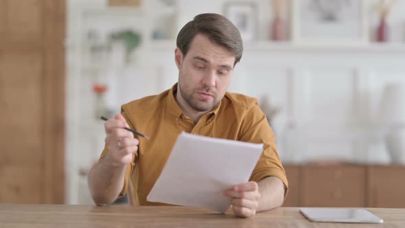 Young Man Reading Documents in Office