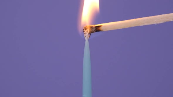 One Blue Cake Candle Burning on a Purple Background