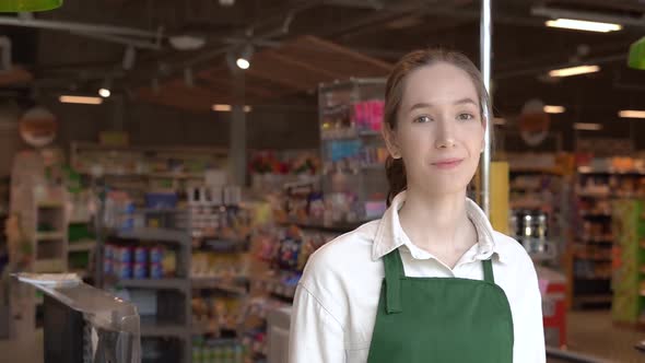 The Girl Supermarket Cashier Smiles for the Camera