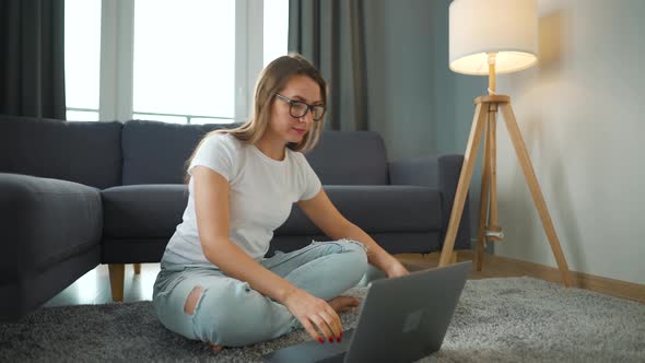 Woman with Glasses is Sitting on the Floor and Makes an Online Purchase Using a Credit Card and