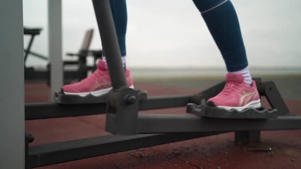 Portrait of woman in sportswear exercising on training apparatus on sports ground