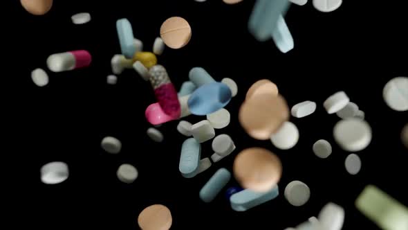 Medical pills falling on black background.