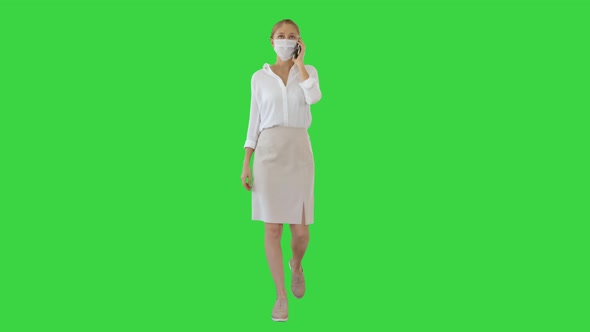 Young Woman Wearing Protective Face Mask Making a Call Walking on a Green Screen, Chroma Key.