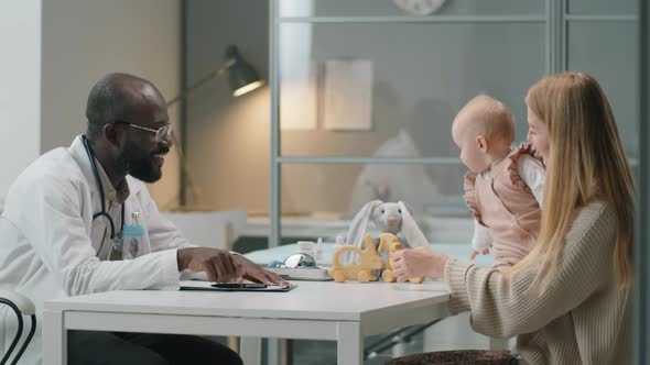 Pediatrician Giving Consultation to Woman with Baby in Clinic