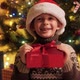 Portrait of Cheerful Smiling Boy with Christmas Present Box Wearing Santa Hat Sitting Next to - VideoHive Item for Sale
