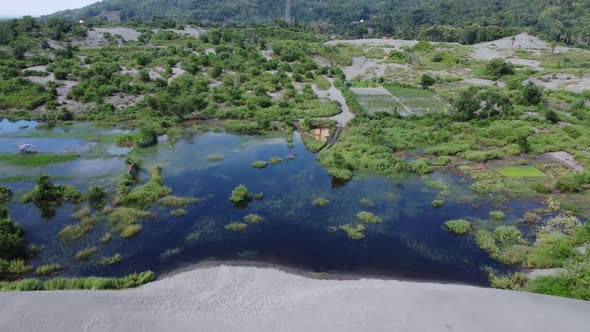 Aerial Drone View Flight over desert with puddles and some green trees in the mountains. White sand,