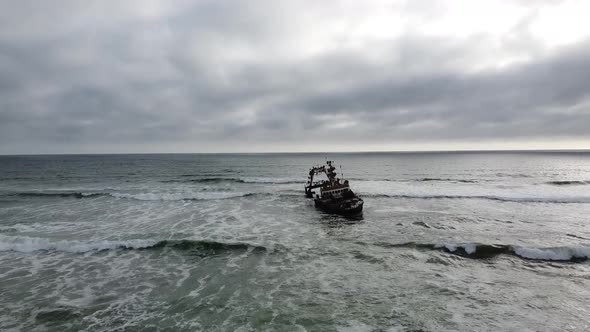 Big old sunken ship near the shore, Skeleton Coast in Namibia, cloudy day
