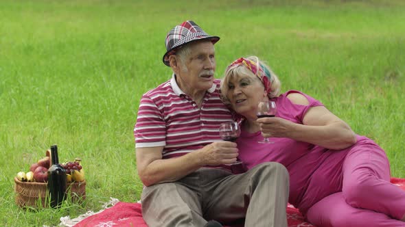 Family Weekend Picnic in Park. Active Senior Old Caucasian Couple Sit on Blanket and Drink Wine