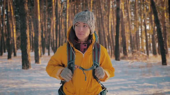 Young Travel Backpacker Woman with Backpack Walking in Snowy Winter Pine Forest