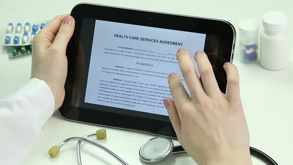 Doctor Reading Agreement, Studying Documents on Tablet. Electronic Documentation