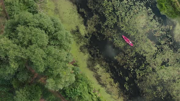 Adventure Activity. Water sports. Red boat or kayak floating on green river top view