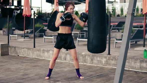 High Pace Video Strong Athletic Female Boxer in Gloves Exercising with a Bag