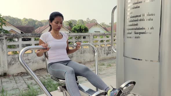 A beautiful woman doing chest workout in an outdoor gym in Thailand - Mid shot