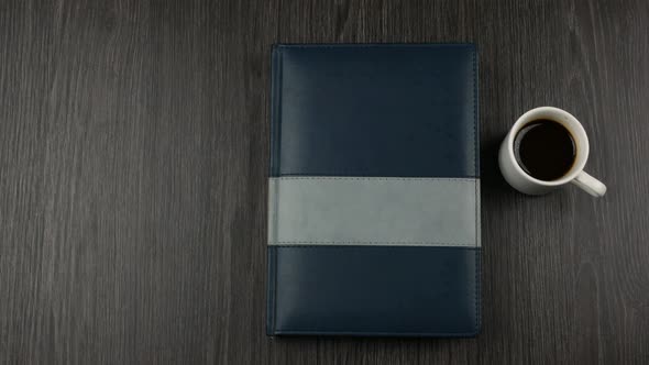 Grey Covered Notepad and Cup of Cofee on Dark Wooden Background. Opening a Notepad for Writing