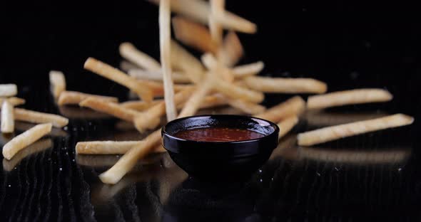 Close-up of Fried Golden Crispy Potatoes, French Fries Falling From Above on Black Table, Cropped