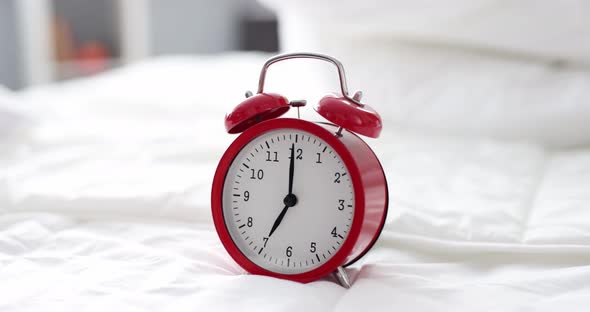 Red Alarm Clock for Seven in Morning is on Bed