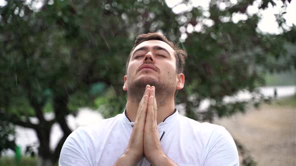 Young Man Praying Being Outside in the Rain