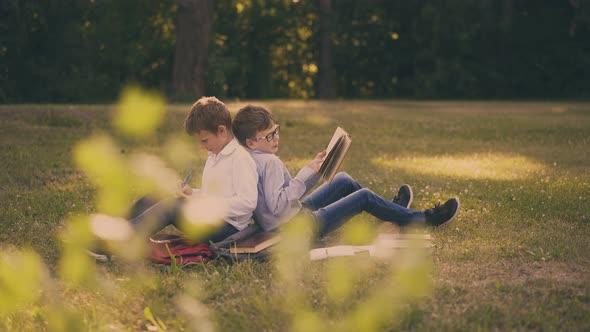 Schoolboys Do Home Task with Books Sitting in Sunny Garden