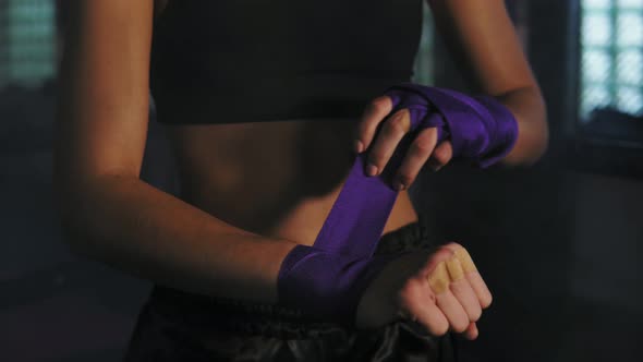 Closeup View of Muay Thai Female Boxer Wrapping Bandages on Her Hands Before Fight in Dark Room with