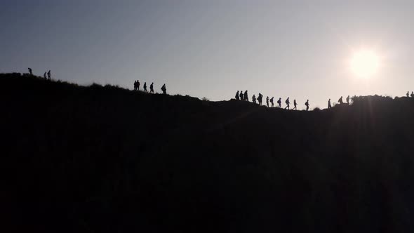 Silhouetted People at the summit of Mout Batur volcano in Bali Indonesia walk along the crater ridge