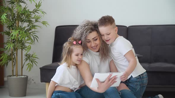 Mom and Daughter and Son Use the Tablet Together in a Cozy Living Room