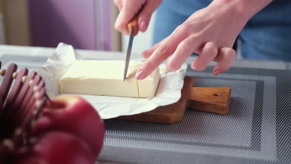Apple Pie Preparation Series  Woman Cuts Butteron Kitchen Table