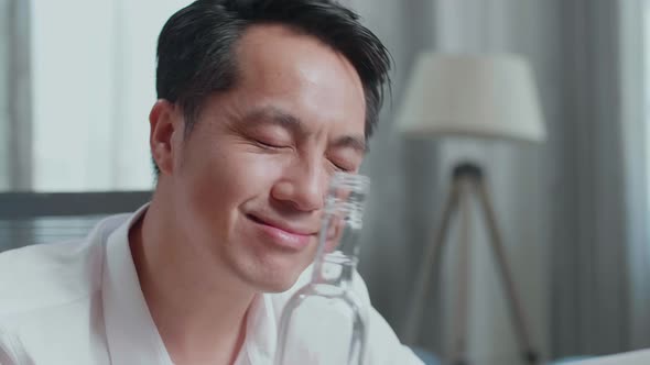 Close Up Of Asian Man Pouring Vodka Before Cheering And Drinking While Having Video Call On Laptop