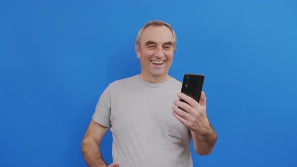 Happy Senior Elderly Man Holding Smart Phone Watching Mobile Video Calling Online Looking Screen