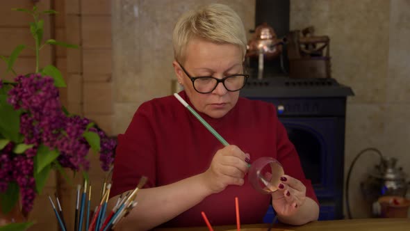 Female Artist Paints Surface of Bracelet with Paintbrush in Stylish Workshop