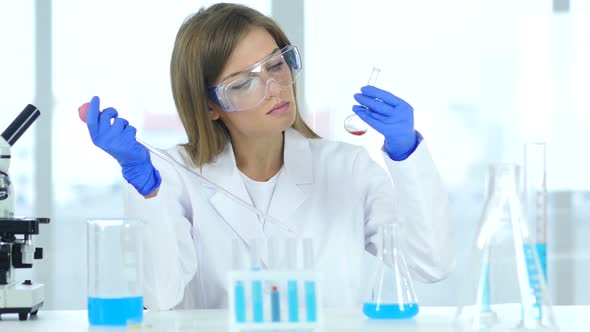 Scientist Looking at Blue Solution in Flask, Laboratory alt