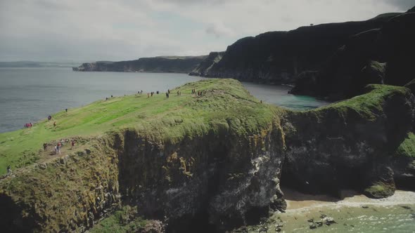 Northern Ireland Carrick Island Aerial View People Hiking on Green Rock Shore