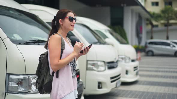 Young Woman Tourist with Smartphone Waiting for a Bus on a Bus Station Travel and Active Lifestyle