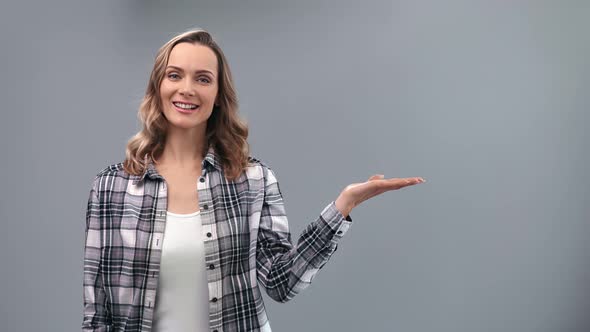 Smiling Casual Woman in Checkered Shirt Presenting Gesture at Copy Space