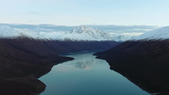Aerial footage of a lake with a reflection of the mountains and peaks in Eklutna Lake, Alaska, USA