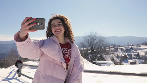 Happy Curly Woman Make Mobile Selfie Video at Snowy Mountain Landscape