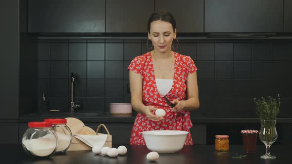 Woman breaking egg into bowl in modern professional kitchen. Food and healthy lifestyle concept