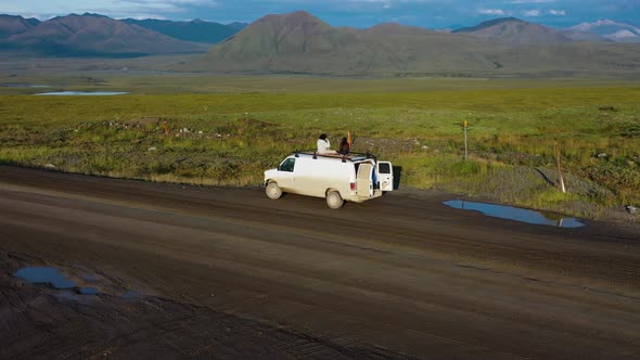 Car trip: Young Couple Hipsters Enjoy Majestic Alaska Wild Nature Landscape Panorama from the Roof o