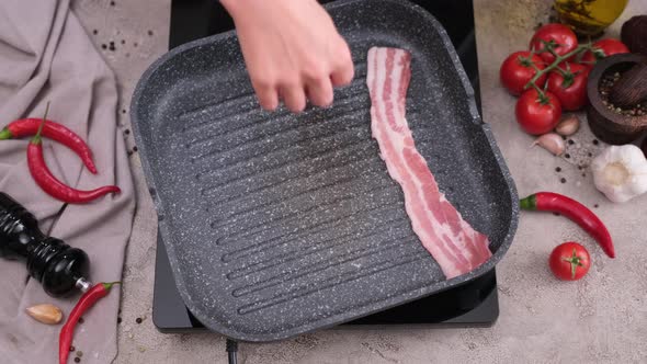 Cooking Pieces of Flavorful Sliced Organic Bacon Fried in Grill Pan