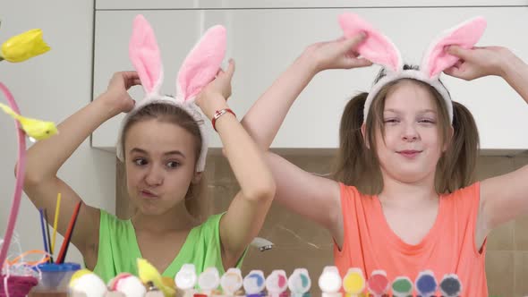 Two Girls Play with Decorated Easter Eggs and Cover Their Eyes with Their Hands