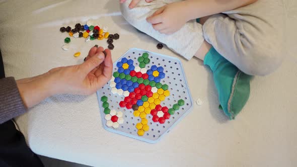 Children's Hands and the Hands of an Adult Play a Children's Game Collect a Colored Mosaic on a